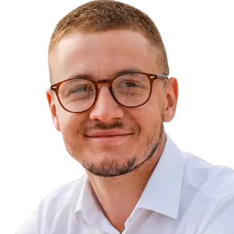 Smiling man with short hair and glasses wearing a white shirt.